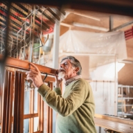 In einer Werkstatt stehen 5 Fensterrahmen, die von einem Tischler begutachtet werden