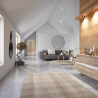 Heller Dachgeschoss-Wohnraum mit grauer Couch und einem Sideboard an einer hohen Holzdekor-Wand.