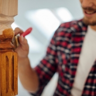 Handwerker lackiert mit einem Pinsel ein künstlerisch verziertes Tischbein