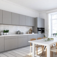 Graue Küchenschränke vor weißer Wand mit weißem Esstisch
