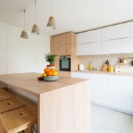 Küche mit Birkenholz und weißen Schränken an der Wand und einem Birkenholz-Tresentisch